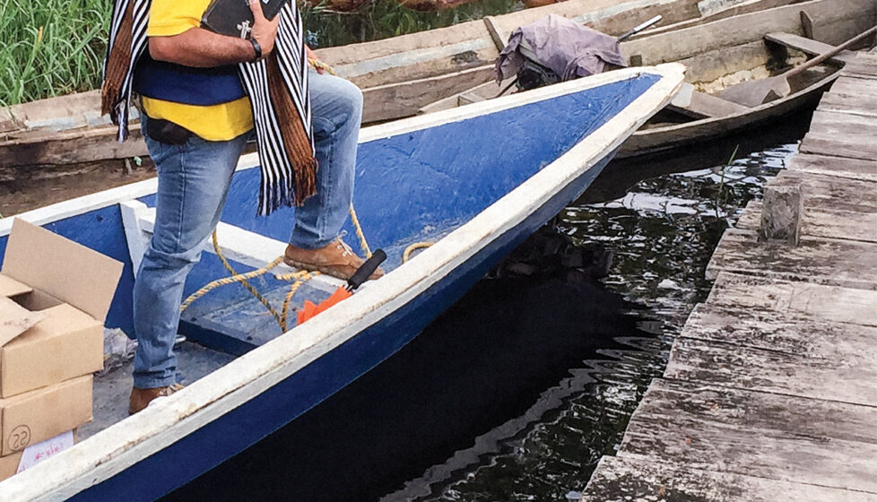 Man standing on a small boat holding a bible