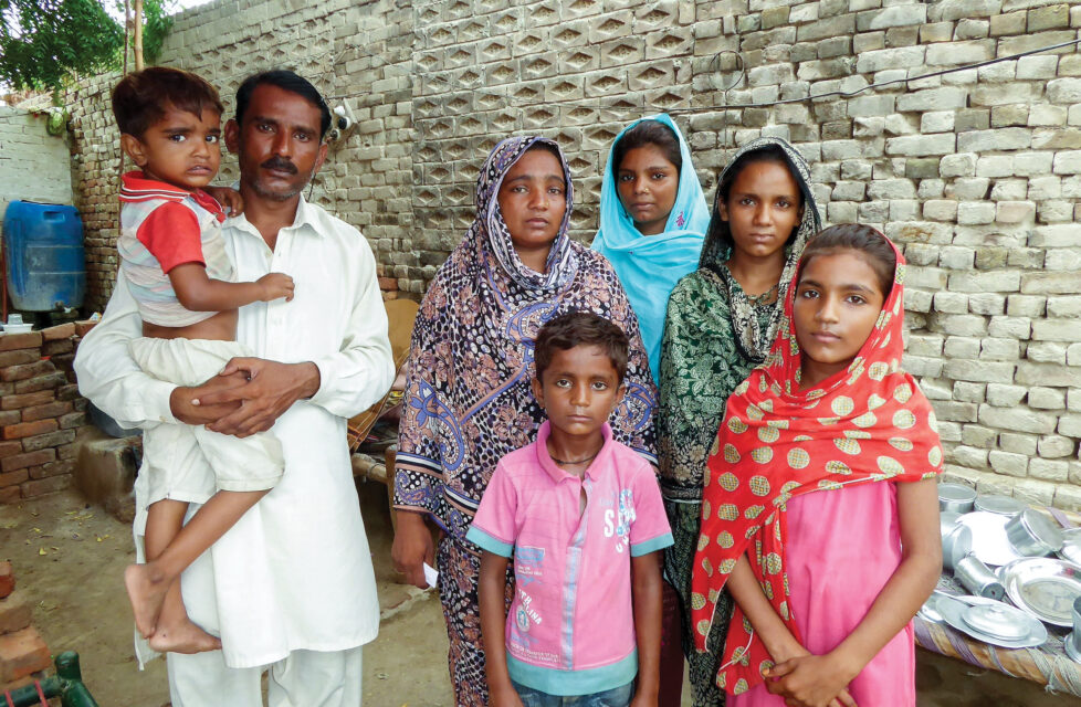 Central Asian family stands in front of wall