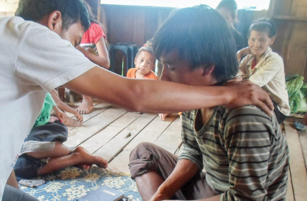 a man prays over a boy in church