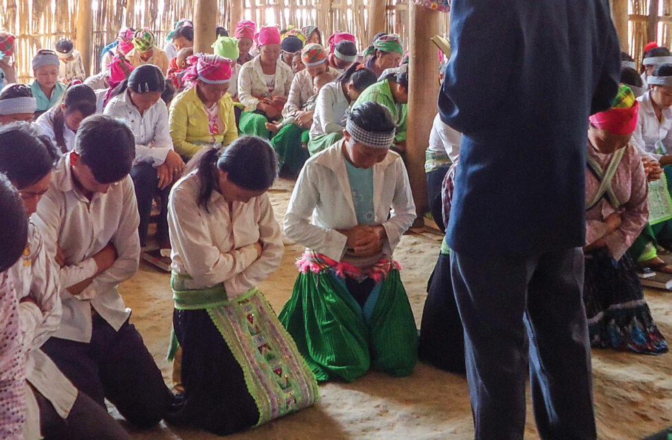 A Man standing in front of his congregation while they pray